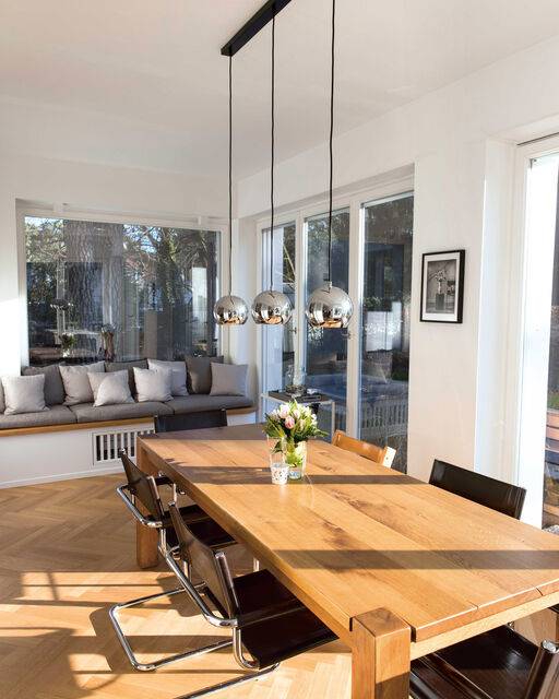 Large wooden dining table stands in a light-flooded room
