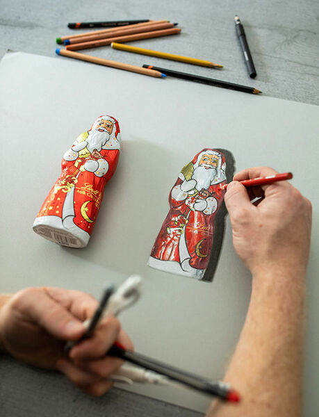 Nahaufnahme von Howard Lees Hand, die einen hyperrealistischen Schoko-Weihnachtsmann zeichnet
