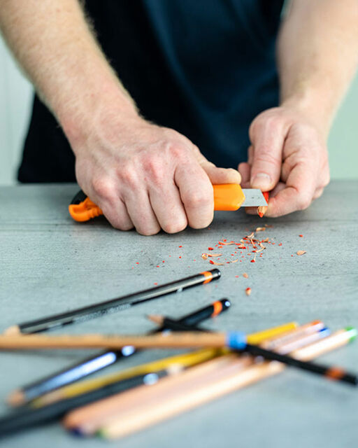 Nahaufnahme von Howard Lees Händen, die mit Cutter-Messer Stifte spitzen