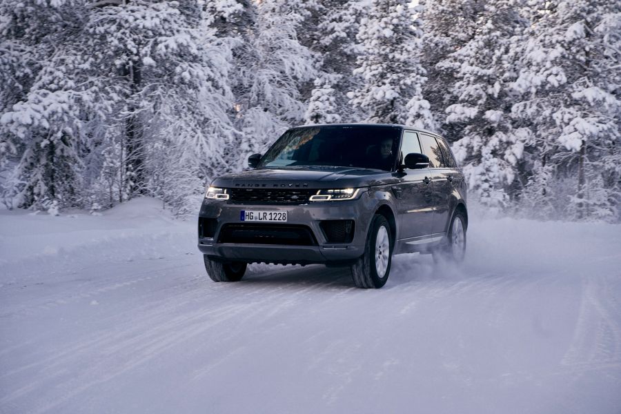 Dark grey Range Rover Sport drives through snowy forest in Lapland