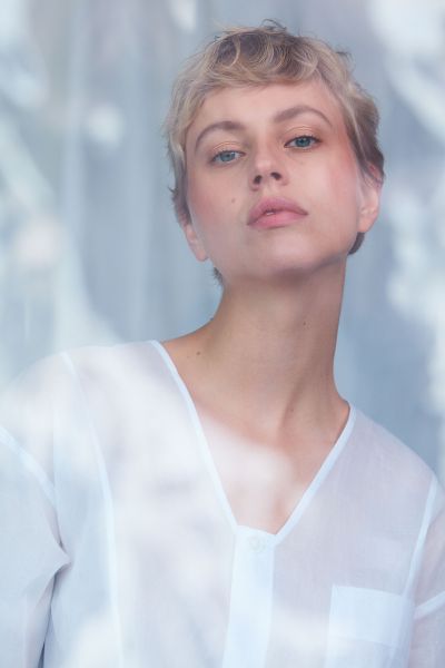 Close up of a young woman with short hair and natural complexion and bluelight