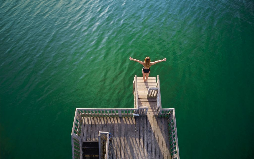 Iris Schmidbauer stands on a springboard with outstretched arms above the Ammersee in Utting