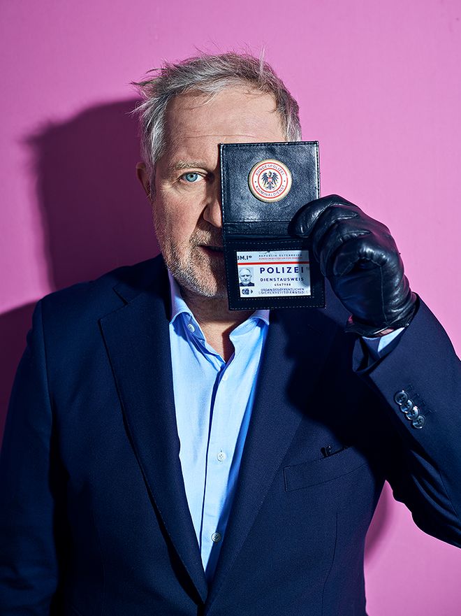 Portrait of Harald Krassnitzer with badge against a pink background