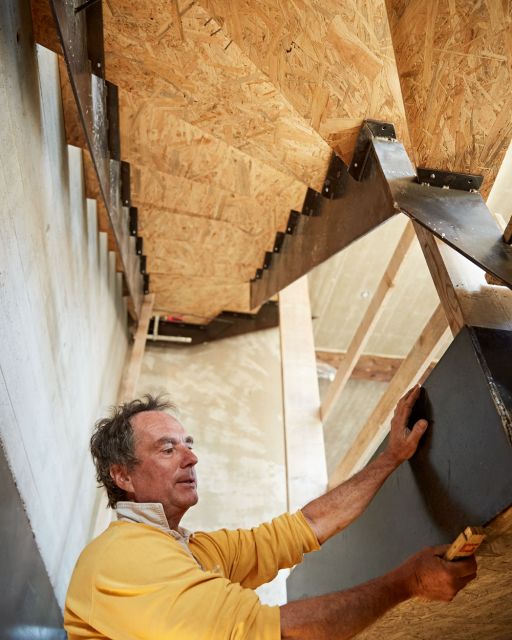 Anderl Friedinger befestigt Holztreppe in Rohbau