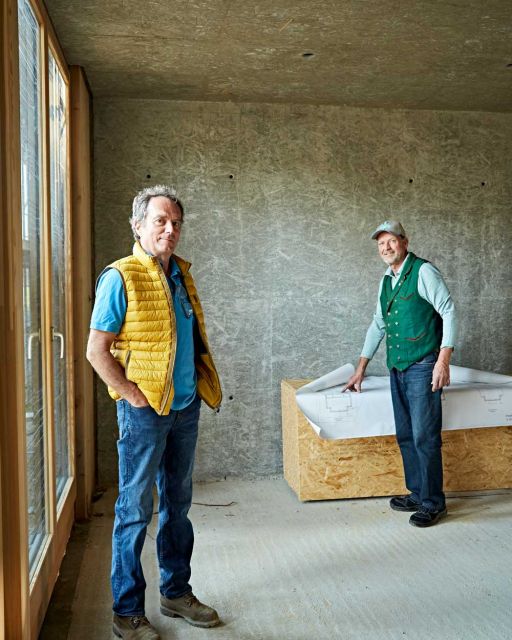 Anderl Friedinger (left) and Karl-Michael Friedinger (right) stand in room with unplastered walls
