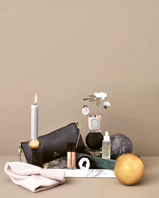 Still life with green and white marble tray, golden and grey ball, candle, beauty products and handbag