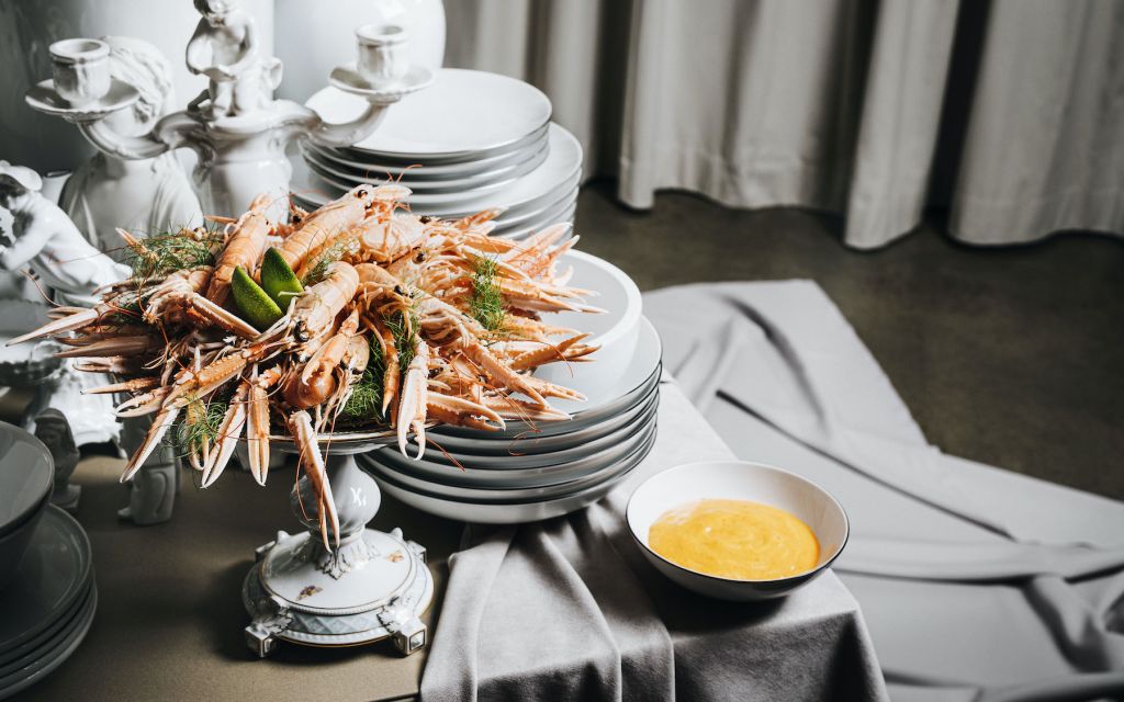 Cooked lobsters with yellow gravy arranged in front of white porcelain plates