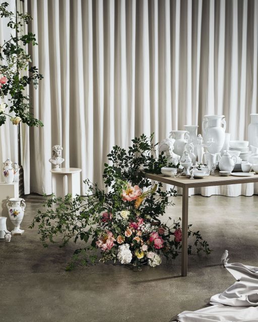 Flower bouquet in front of table laid out with white porcelain tablewares and beige curtain