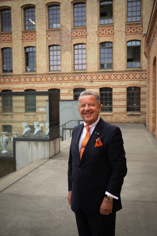 Jörg Woltmann stands smiling in the courtyard of the Royal Porcelain Manufactory in Berlin