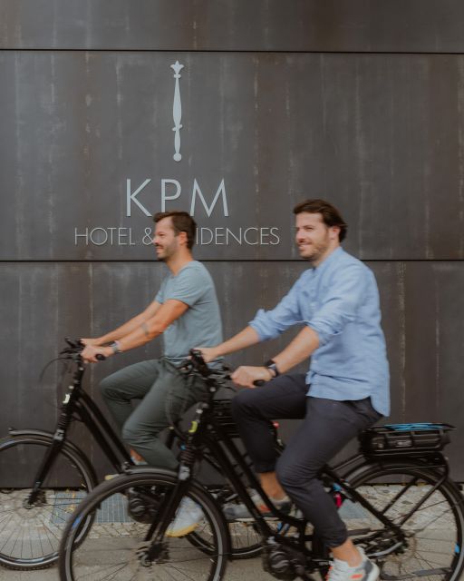 Two men riding bicycles past KPM Hotel & Residences