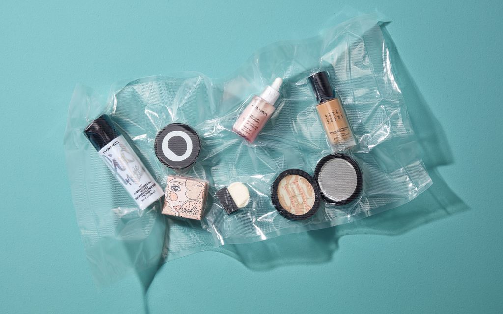 Makeup products wrapped in foil lie on turquoise background