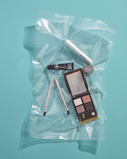 Still life with makeup products wrapped in foil on turquoise background