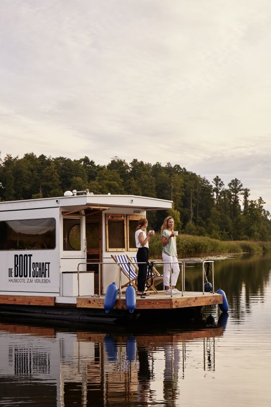 Hausboot beim Sonnenuntergang zwei Frauen mit Tassen in der Hand