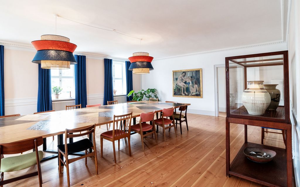 Room with long dining table, shelf and colorful lamps in design hotel Kanalhuset