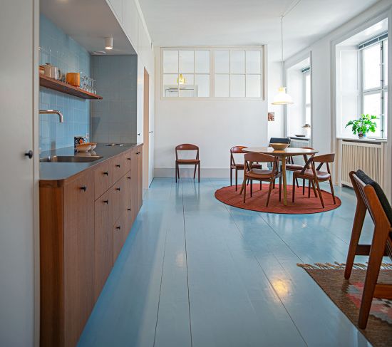 Kitchen with blue floor, wooden cabinets and BORA system in design hotel Kanalhuset