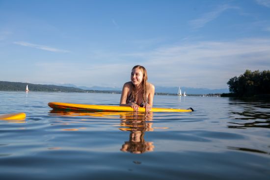 Junge Frau stützt sich auf SUP Board im Wasser