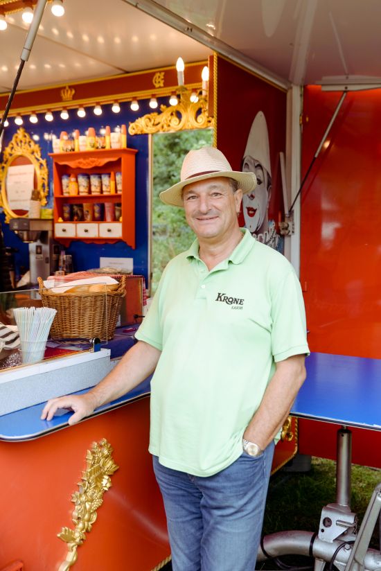 Mann mit hellgrünem T-Shirt steht vor Wagen mit Snacks