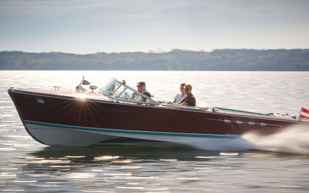 Riva Boot mit vier Personen fährt auf Starnberger See