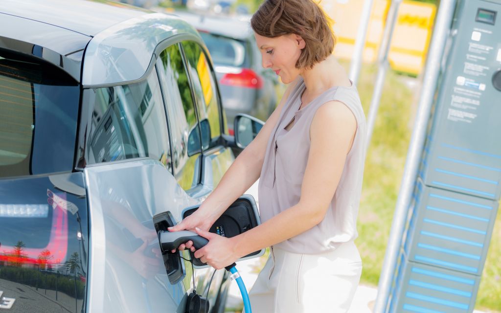 Woman charging electric car at charging station