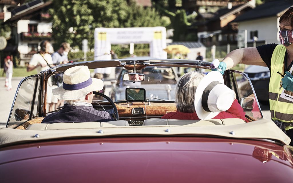 Two people drive up in red vintage convertible