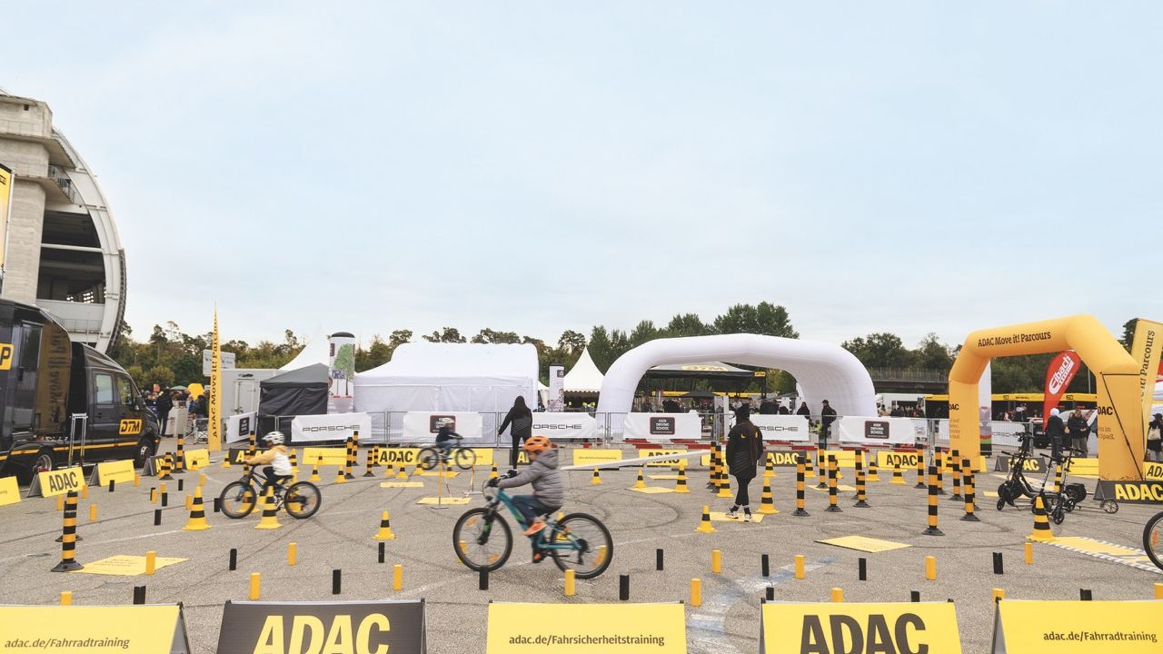 Kinder fahren mit Fahrrädern durch den ADAC move it! Fahrsicherheitsparcours in der DTM-Fanzone.