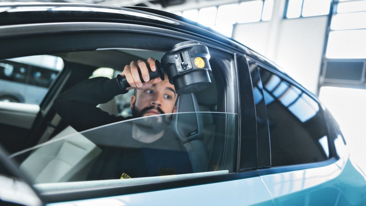 Ein Mann testet den Einklemmschutz am geöffneten Fenster eines Autos.