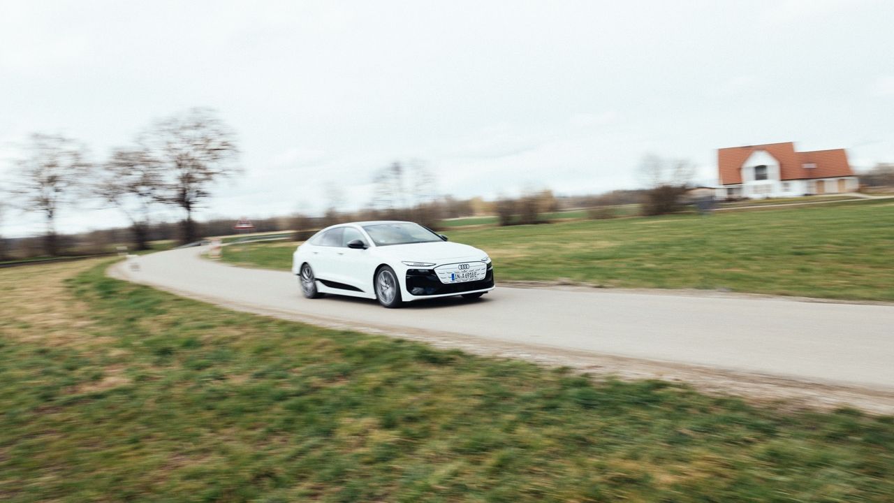 Weißer Audi A6 Sportback e-tron fährt auf einer kurvigen Landstraße