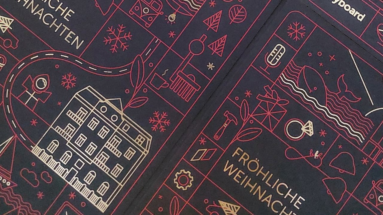 A dark red Christmas card featuring gold and red line art with various icons such as buildings, snowflakes, and the lettering "FRÖHLICHE WEIHNACHTEN."
